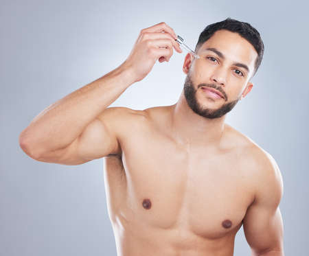 Say goodbye to wrinkles with retinol. Studio shot of a handsome young man applying serum to his face against a grey background.の写真素材