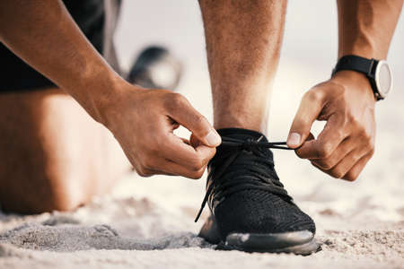 Nothing can stop you now. an unrecognizable man tying his shoelaces while out for a workout.の写真素材