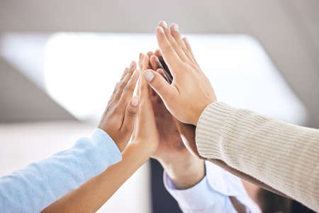 We can do this. a group of business people high fiving one another.
