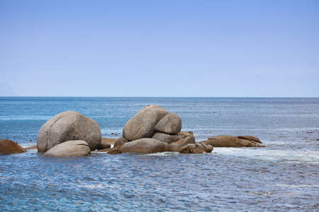Copy space, sea rocks and ocean view of calm, serene and peaceful beach with blue sky, waves and copyspace. Relaxing, tropical and remote seascape with boulders on a secluded coastal island in summerの写真素材