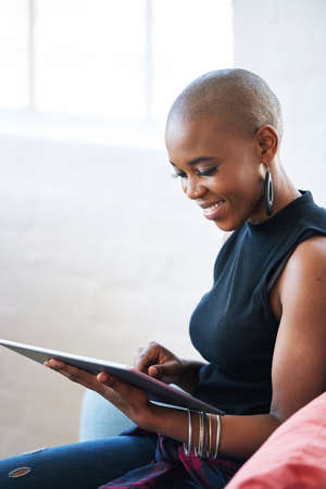 Bald african american woman using digital tablet computer at homeの写真素材