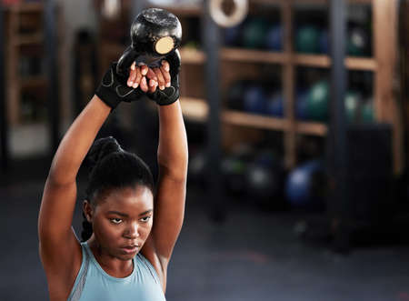 Giving up is not an option. a woman working out with a kettle bell at the gym.の写真素材
