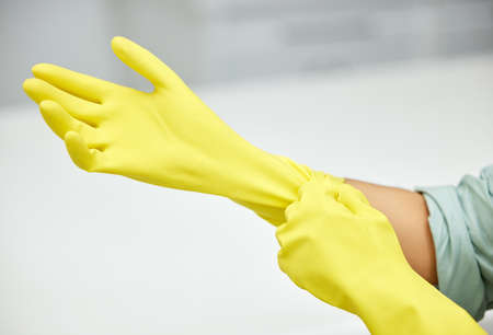 Im ready to start cleaning. Closeup shot of a woman putting on gloves before cleaning.