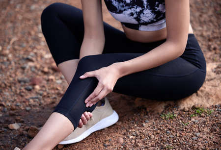 Now I definitely regret not warming up. a woman suffering from a knee injury while out on a trail.