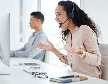 How does she do it. a young call centre agent cheering while working on a computer in an office with...