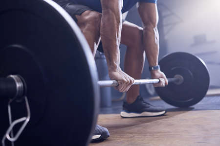 Lift the way to a healthier life. an unrecognisable man working out with a barbell at the gym.の写真素材