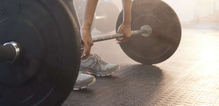 Deadlifts target full-body activation. Closeup shot of an unrecognisable woman exercising with a...
