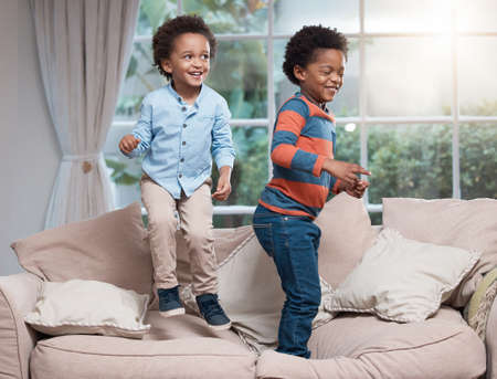 Letting out all their energy. two little boys jumping on a sofa at home.の写真素材