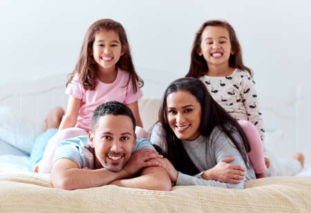 Your family is the best team youll ever have. a couple lying on bed with their two daughters.