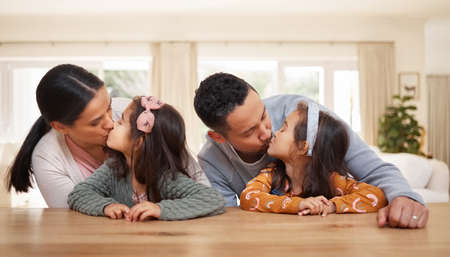 Both of you are our world. a mother and father giving their daughters kisses.の写真素材