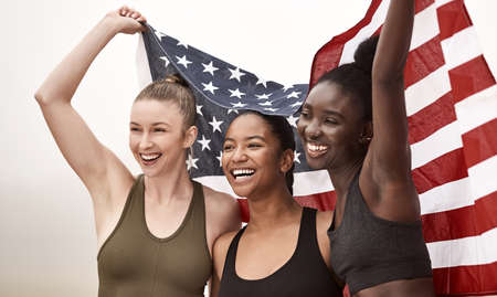 The only team you need on your side. a young sports team holding the american flag.の写真素材