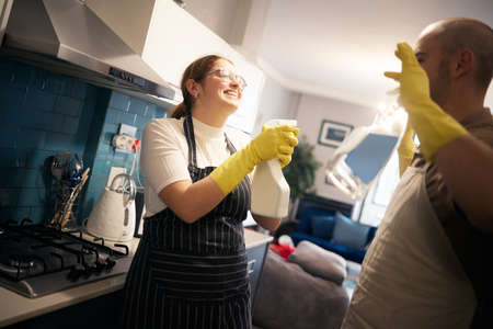 I surrender I promise. a young couple playing while they clean their kitchen.の写真素材