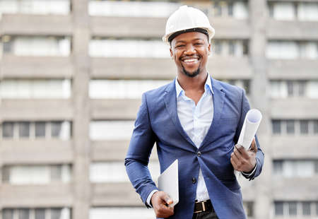 Construction in progress. Cropped portrait of a handsome young male engineer holding blueprints and a tablet while standing on a construction site.の写真素材