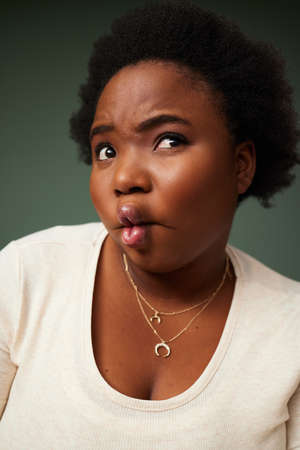 Dare to be you. an attractive young woman pulling a funny face while posing against a green...