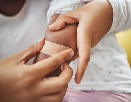 Well just apply it there. an unrecognizable mother applying a bandaid to her daughters arm at home.の写真素材
