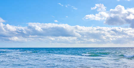 Beautiful, blue ocean view of the sea with white clouds on a beach day in summer. Outdoors landscape of calm water, sky and waves in nature. Peaceful outdoor coastal setting outside.の写真素材