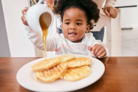 Something sweet for my sweet tooth. a little girl pouring honey over some waffles.の写真素材