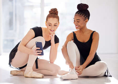 Can you believe they sent me that. two ballet dancers using a smartphone together.の写真素材