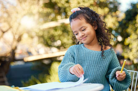 Feeling smarter every day. a little girl completing homework in her yard.の写真素材