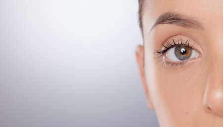 Closeup shot of a young womans eyes against a grey background.