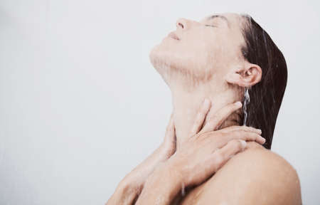 Let the steam soothe you. a young woman rinsing her hair during a shower.の写真素材