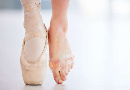 The plus side is that I finally perfected my pointe technique. a young ballerina wearing a pointe shoe on one foot and band aids on her barefoot.の写真素材