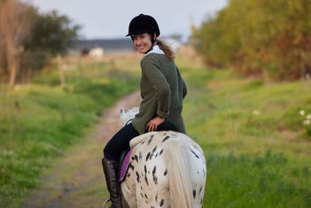 The essential joy of being with horses. a young woman riding her horses outside on a field.の写真素材
