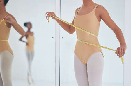 Just a few more inches to go. an unrecognizable ballet dancer measuring her waist during a...