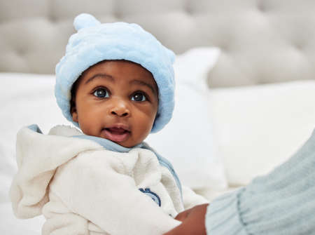 Did you just call me cute. an adorable baby boy sitting on a bed.