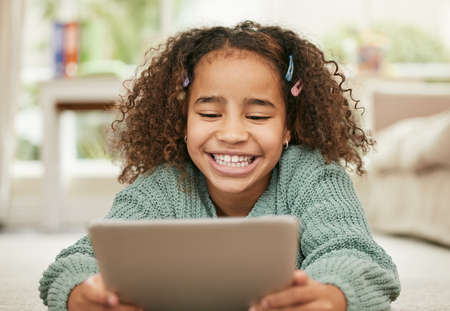 There are many ways of learning now. a little girl using a digital tablet at home.