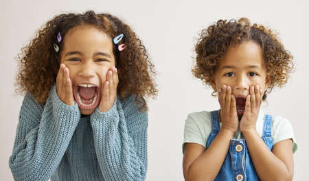 Oh my goodness. two adorable little girls standing together and looking surprised.の写真素材