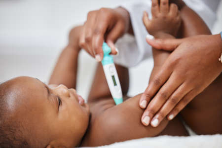 Youre healthy as horse. a little baby having her temperature taken by a doctor with a thermometer.