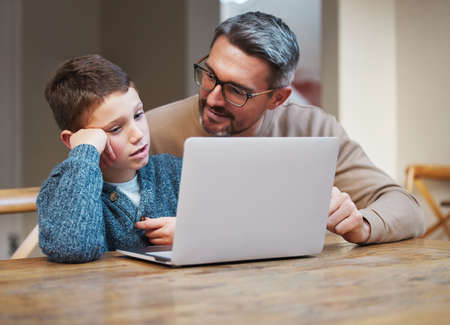 I know its tough but you can do it. a father and son team using a laptop to complete school work.の写真素材