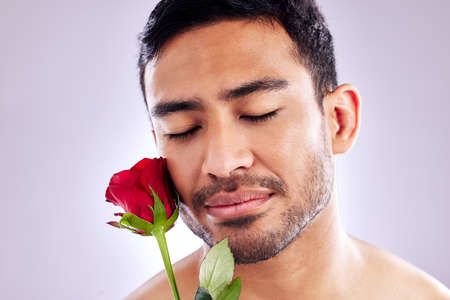 Wild but beautiful. Studio shot of a handsome young man posing with a red rose.の写真素材