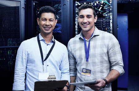 Need a network upgrade Were your guys. two young men working together in a server room.の写真素材