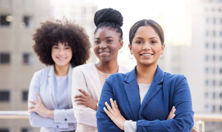 Getting closer to success as a team. a diverse group of businesswomen standing outside on the balcony with their arms folded.の写真素材