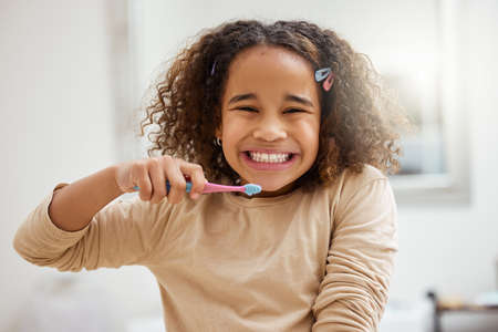 Encourage kids to develop positive hygiene habits. Portrait of an adorable little girl brushing her teeth in a bathroom at home.の写真素材