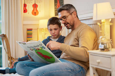 Enjoying some quality reading time together. a father and son reading a book about dinosaurs...