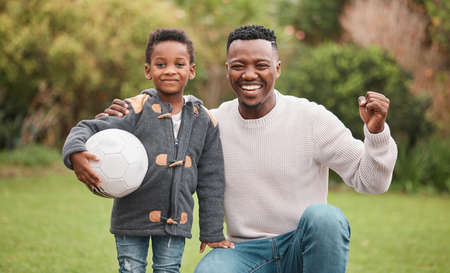 Dad will always cheer him on. Portrait of a father and his son playing with a soccer ball together outdoors.の写真素材