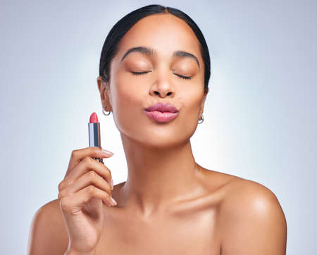 Modesty will get you mileage. a beautiful young woman posing with her perfect shade of lipstick against a grey background.の写真素材