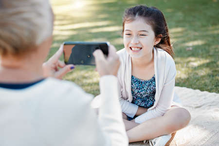 These pics are going to turn out so cute. a little girl posing for photos with her grandmother outdoors.の写真素材
