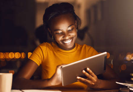 Beautiful, happy and smiling female student using a tablet to browse the internet, do research or...