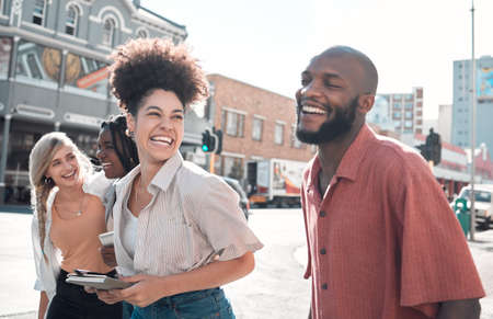 Happy, laughing group of friends walking and smiling together in a city. Casual excited people enjoying a relaxing time in an urban town. Cheerful young coworkers having fun on their day off.の写真素材