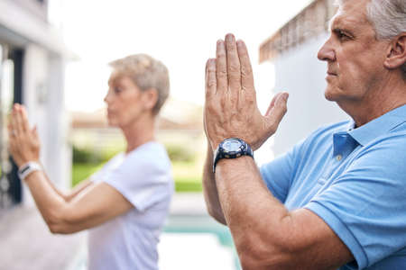 Calm is the best way to live. a mature couple meditating together outdoors.の写真素材