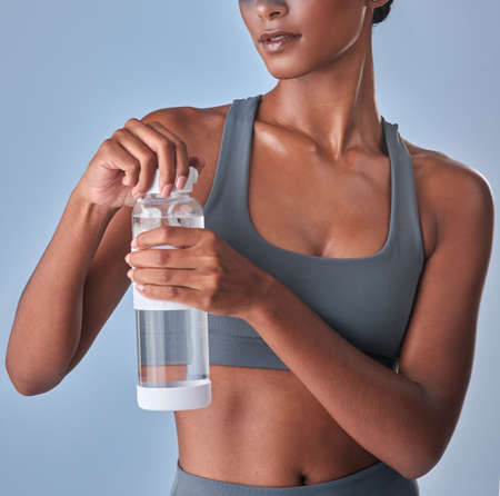 Hydration and health go hand in hand. Studio shot of a fit young woman drinking bottled water...