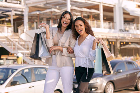 You can never have enough things. two attractive young women standing outside together and bonding while shopping in the city.の写真素材