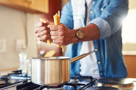 I know how to make a good spaghetti. a man breaking spaghetti before boiling it.の写真素材