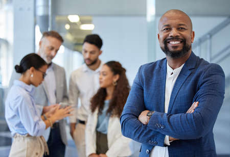 You can do a lot with a little determination. Portrait of a mature businessman standing in an office with his colleagues in the background.の写真素材