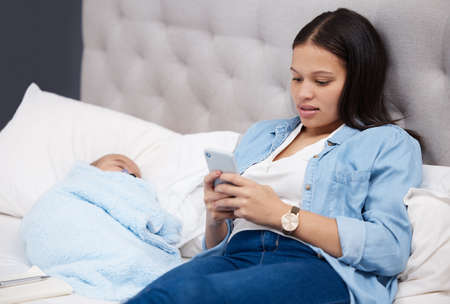 He was the size of a half loaf of bread. a mother using her phone while her baby sleeps at home.
