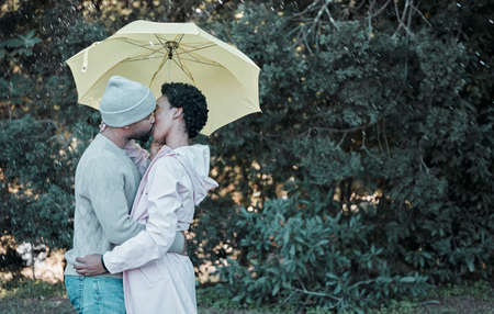 The best kisses are the ones shared in the rain. a young couple kissing while standing under an umbrella.の写真素材